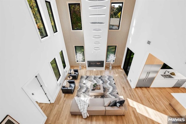 living room featuring a high ceiling, light wood-type flooring, and a fireplace