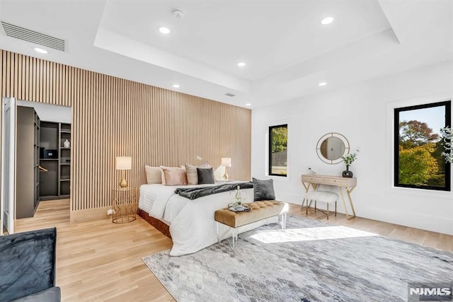 bedroom with a tray ceiling and light wood-type flooring