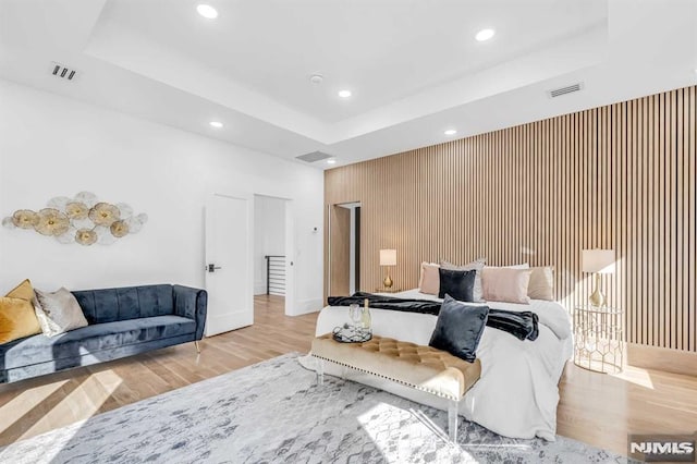 bedroom featuring a tray ceiling and light wood-type flooring