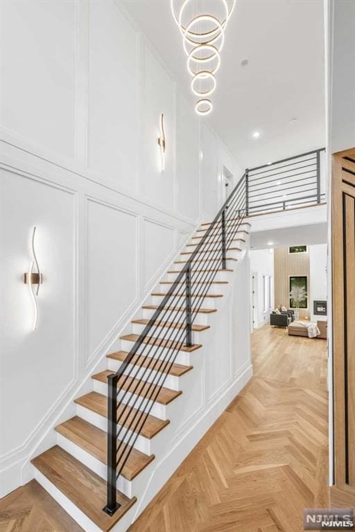 stairs featuring parquet floors and a notable chandelier