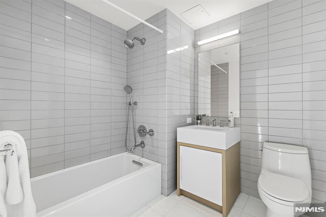 full bathroom with vanity, tiled shower / bath, tile walls, and toilet