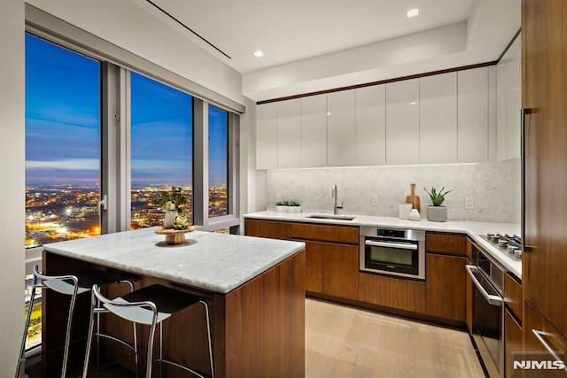 kitchen with sink, a center island, stainless steel appliances, decorative backsplash, and white cabinets