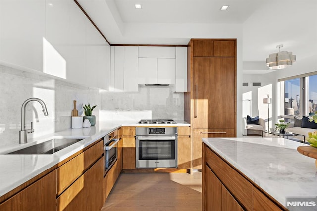 kitchen featuring sink, wood-type flooring, white cabinets, stainless steel appliances, and backsplash