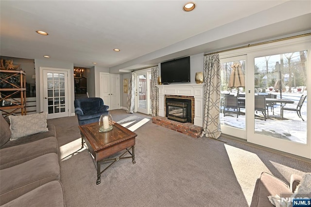 carpeted living room featuring a brick fireplace and french doors