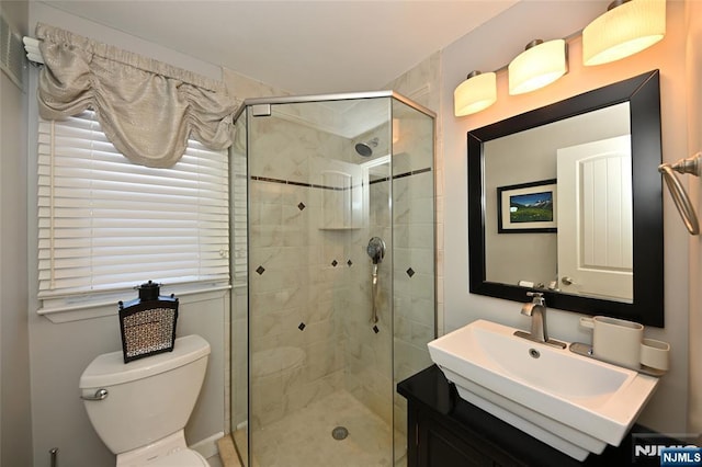 bathroom featuring a shower with door, vanity, and toilet