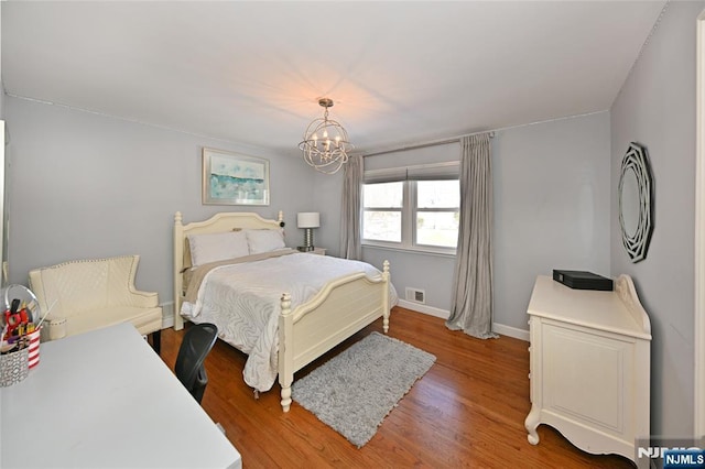 bedroom with hardwood / wood-style flooring and an inviting chandelier