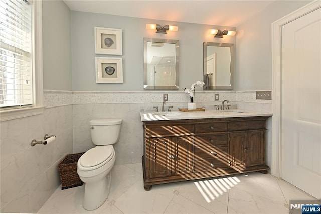 bathroom with vanity, tile walls, and toilet