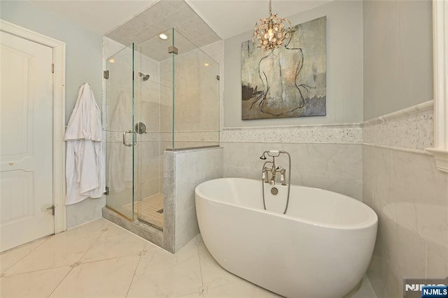 bathroom featuring shower with separate bathtub and tile walls