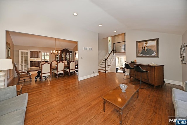 living room featuring lofted ceiling, a chandelier, and hardwood / wood-style floors