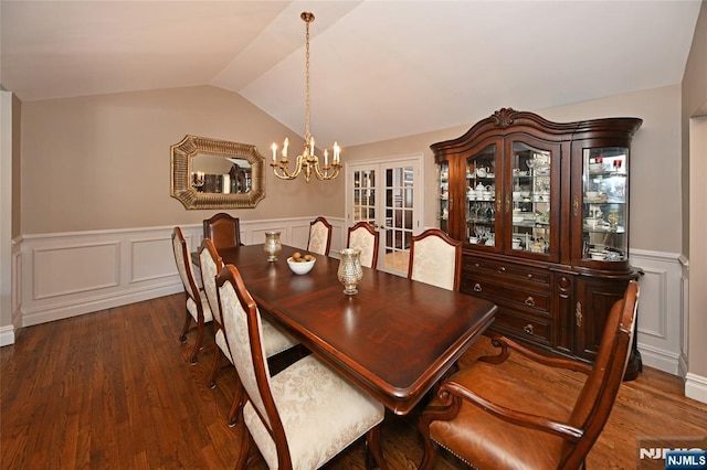 dining room with dark wood-type flooring, an inviting chandelier, vaulted ceiling, and french doors