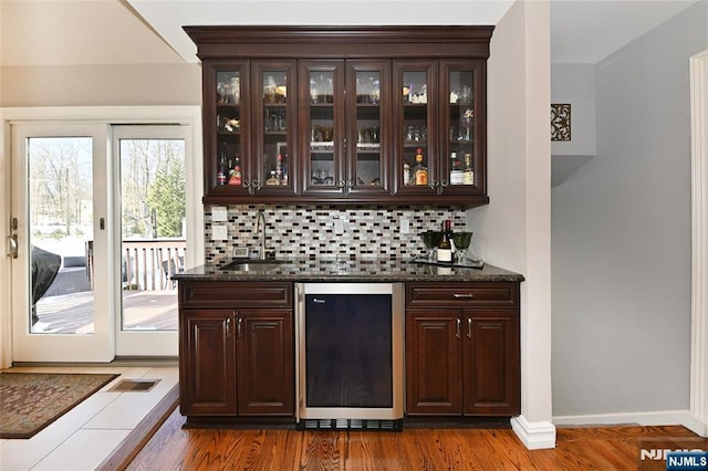 bar with dark brown cabinets, sink, and dark stone countertops