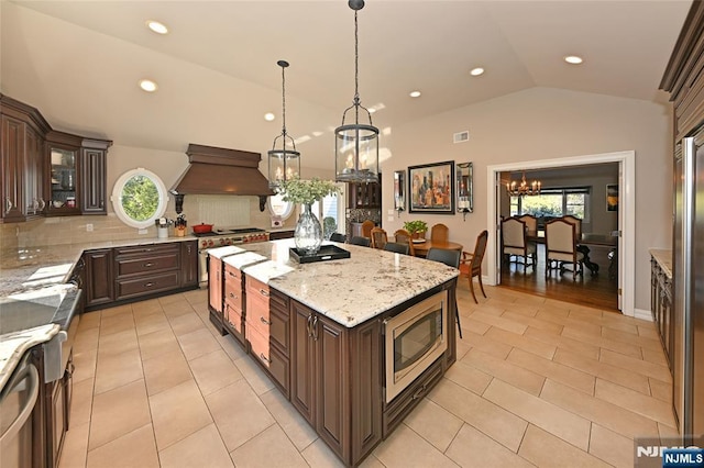 kitchen featuring lofted ceiling, premium range hood, stainless steel appliances, a center island, and decorative light fixtures