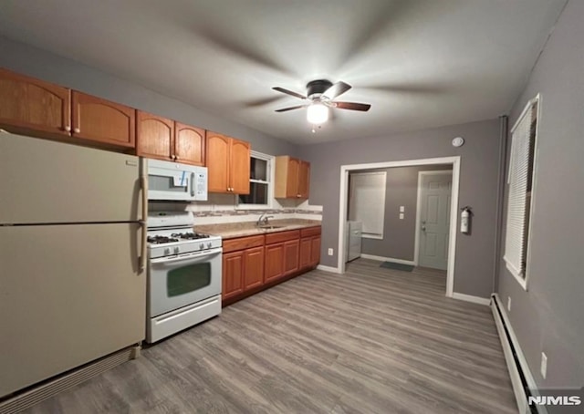 kitchen with sink, white appliances, ceiling fan, baseboard heating, and light hardwood / wood-style floors