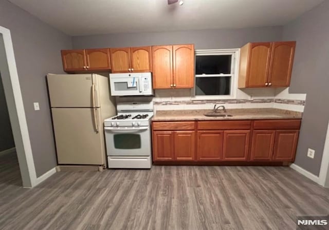 kitchen with sink, white appliances, and hardwood / wood-style floors