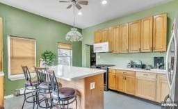 kitchen with pendant lighting, ceiling fan, stainless steel appliances, a center island, and a kitchen bar