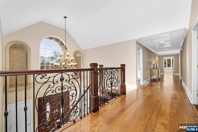 hallway featuring an inviting chandelier, a healthy amount of sunlight, vaulted ceiling, and hardwood / wood-style floors