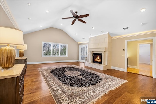 living room with a fireplace, lofted ceiling, hardwood / wood-style flooring, ornamental molding, and ceiling fan