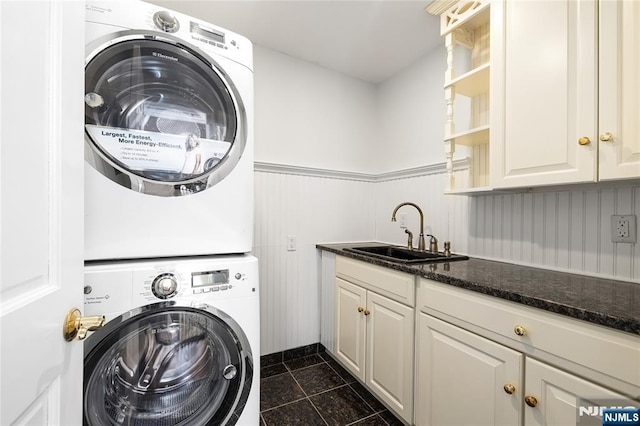 clothes washing area featuring cabinets, stacked washer / dryer, and sink