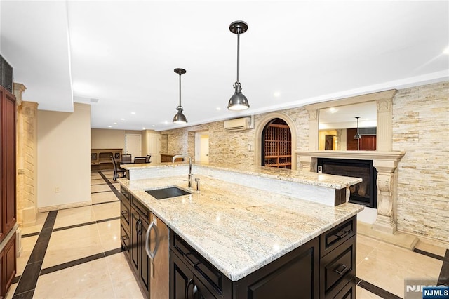 kitchen featuring pendant lighting, light stone countertops, sink, and an AC wall unit