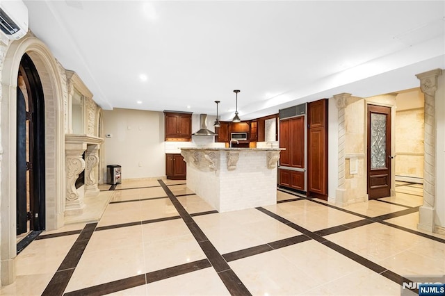 kitchen featuring wall chimney exhaust hood, a wall mounted AC, stainless steel microwave, a kitchen island, and a fireplace