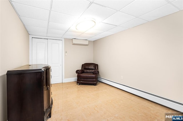 sitting room with baseboard heating, a wall mounted air conditioner, light tile patterned floors, and a drop ceiling