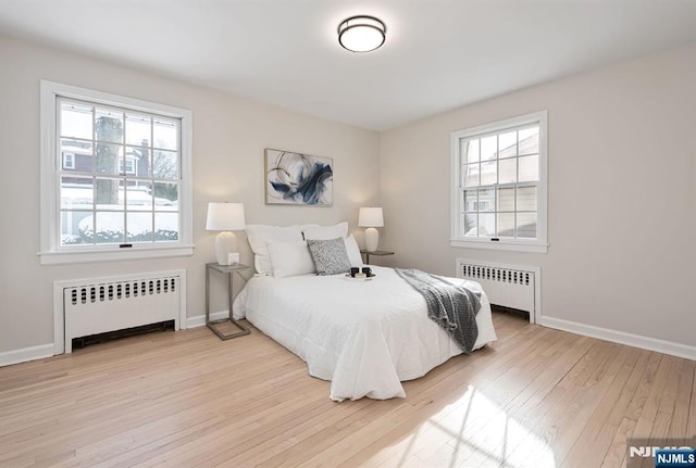 bedroom with multiple windows, radiator, and light hardwood / wood-style flooring