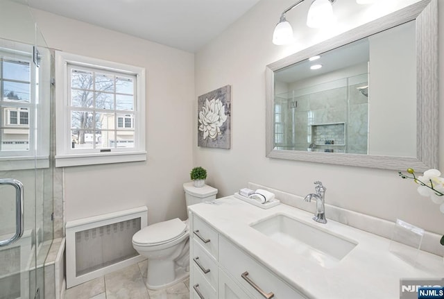 bathroom with vanity, radiator, a shower with door, and toilet