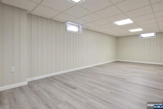 basement with plenty of natural light, a paneled ceiling, and light hardwood / wood-style flooring