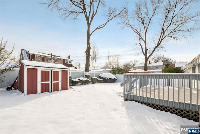 yard covered in snow featuring a wooden deck and a shed