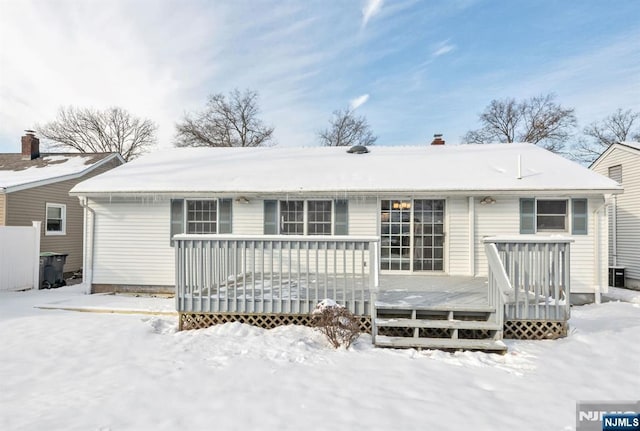 snow covered back of property featuring a wooden deck