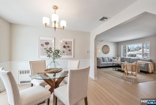 dining space featuring radiator heating unit, a chandelier, and light hardwood / wood-style floors