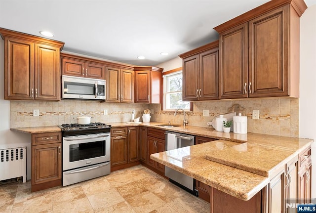 kitchen with sink, radiator, backsplash, stainless steel appliances, and kitchen peninsula