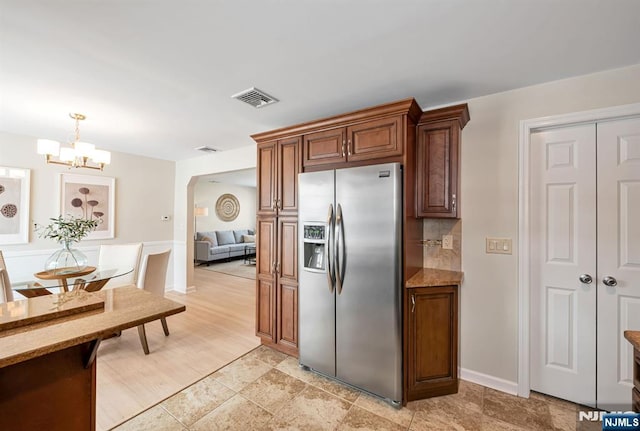 kitchen featuring an inviting chandelier, stainless steel fridge with ice dispenser, decorative light fixtures, and tasteful backsplash