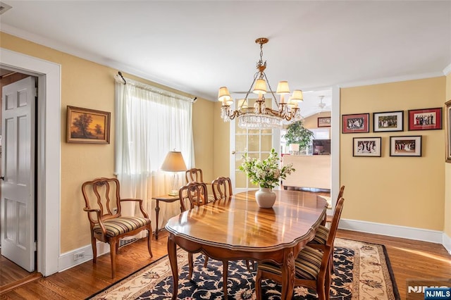 dining space with crown molding, hardwood / wood-style floors, and a notable chandelier