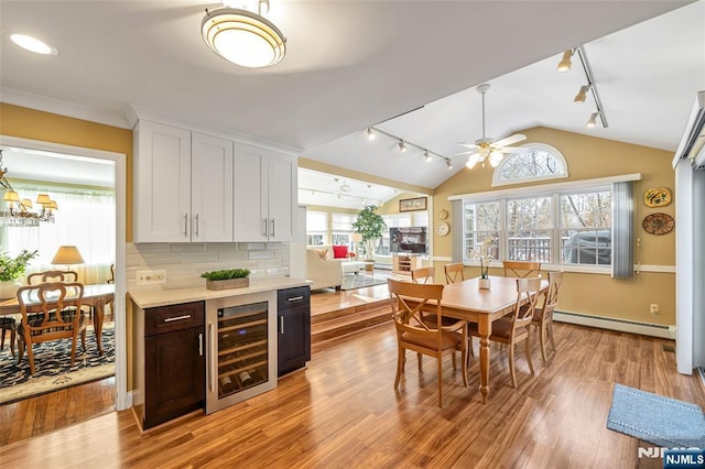 kitchen featuring a baseboard radiator, lofted ceiling, white cabinets, beverage cooler, and backsplash