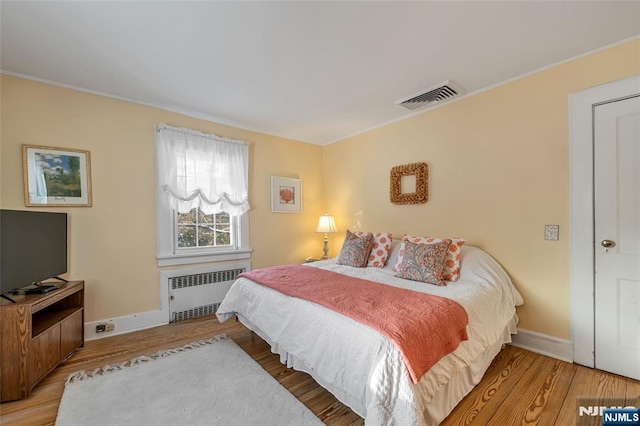 bedroom with hardwood / wood-style flooring and radiator