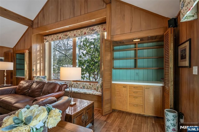 living room featuring vaulted ceiling, light hardwood / wood-style floors, and wood walls