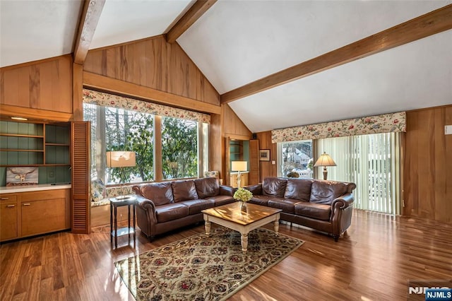 living room with wooden walls, high vaulted ceiling, beam ceiling, and hardwood / wood-style floors