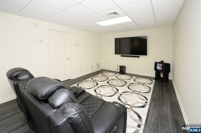 living room with dark wood-type flooring and a drop ceiling