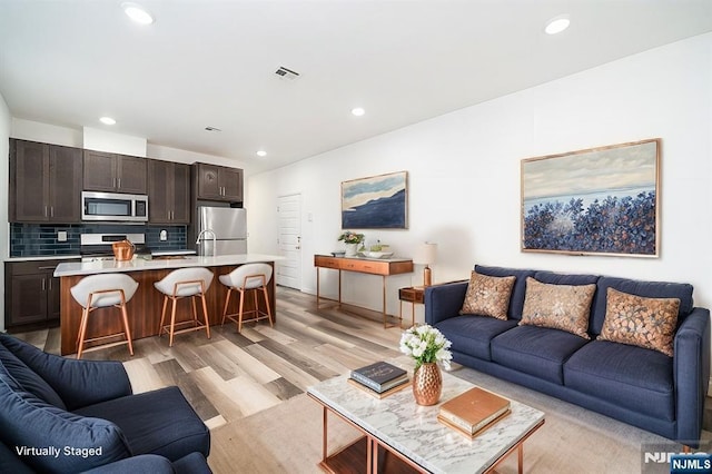 living room with recessed lighting, visible vents, and light wood-type flooring