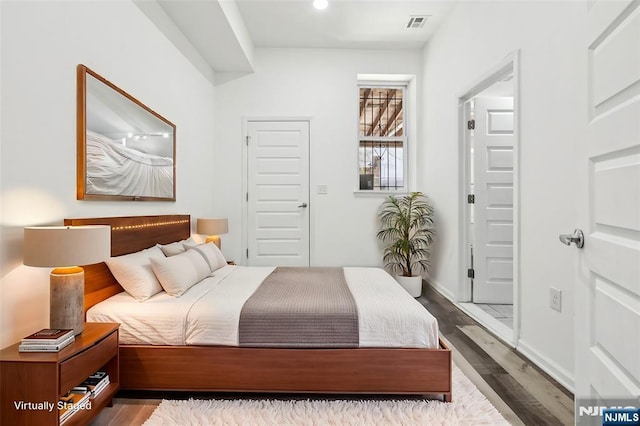 bedroom with visible vents, baseboards, and dark wood-type flooring