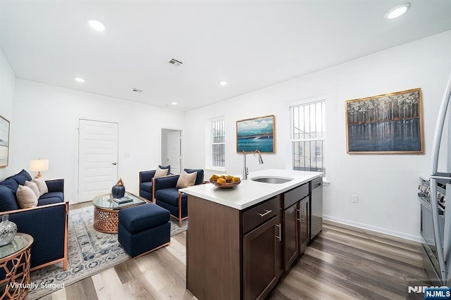 kitchen featuring open floor plan, stainless steel dishwasher, light countertops, and a sink