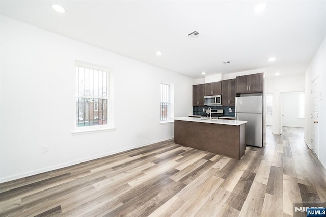 kitchen featuring dark brown cabinetry, appliances with stainless steel finishes, a healthy amount of sunlight, and light countertops