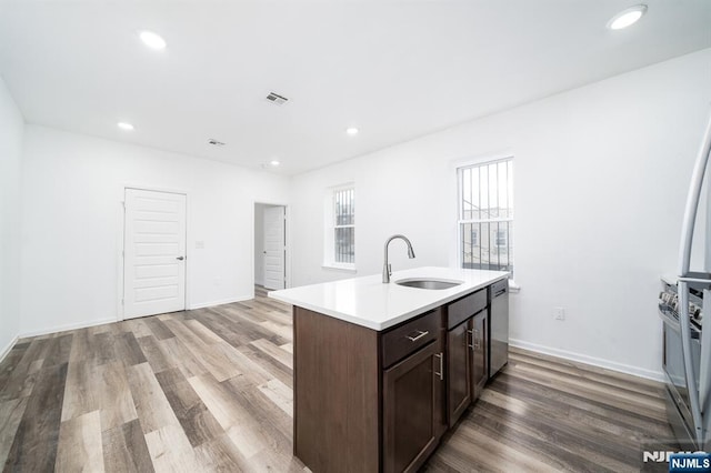 kitchen featuring light countertops, recessed lighting, appliances with stainless steel finishes, wood finished floors, and a sink