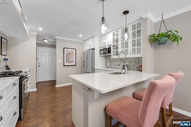 kitchen featuring sink, stainless steel appliances, white cabinets, a kitchen bar, and kitchen peninsula