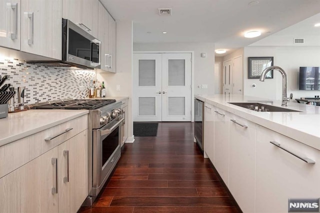 kitchen with french doors, sink, appliances with stainless steel finishes, dark hardwood / wood-style flooring, and decorative backsplash