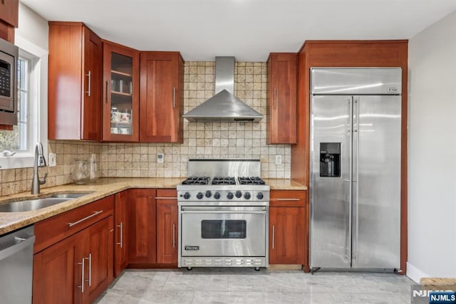 kitchen featuring sink, backsplash, premium appliances, light stone countertops, and wall chimney range hood