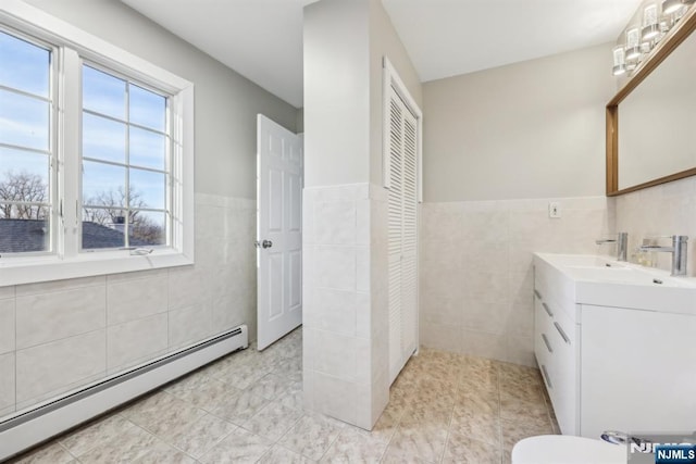 bathroom with tile patterned flooring, vanity, tile walls, and baseboard heating