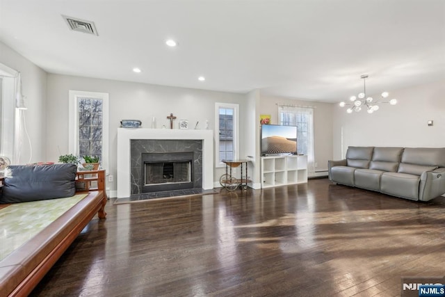 living room with an inviting chandelier, a fireplace, dark hardwood / wood-style floors, and a baseboard heating unit