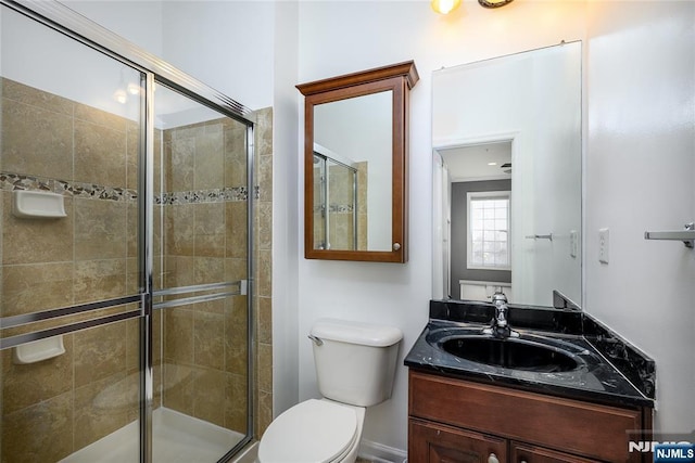 bathroom with vanity, toilet, and a shower with shower door